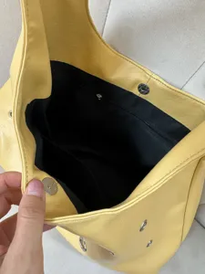 Detail shot of the yellow PU leather underarm bag interior, featuring black lining and zip pocket.