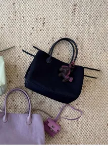 Close up detail of black nylon tote bag featuring cute horse pendant and minimalist design style