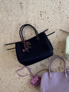 Detail view of niche design minimalist nylon tote bag with chic horse charm and handles.