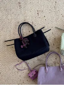 Minimalist nylon tote bag with leather charm, casual daily shoulder handbag detail.