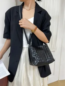 Detail shot of black woven leather bucket handbag, stylish shoulder and crossbody style.