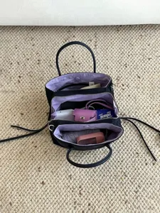 Minimalist multi-compartment nylon handbag with purple interior lining for daily use.