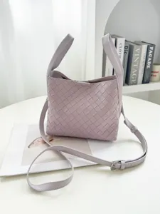 Detailed view of lavender woven leather bucket bag with top handles and adjustable strap.