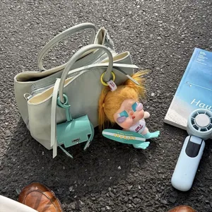Detail view of stylish nylon tote bag with multiple compartments and cute doll charm.