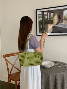Chic green woven shoulder tote bag detail shot in elegant interior scene, perfect for summer.