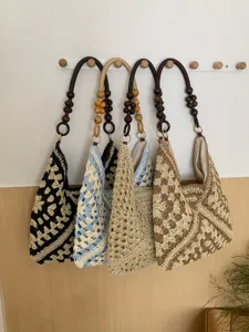 Detail view of woven straw shoulder tote bags hanging on wall, summer beach vacation style.