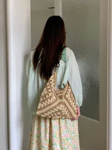 Detailed view of a handmade crochet straw shoulder bag with wooden beads strap for summer.