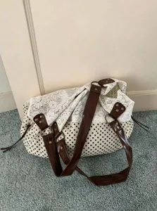 Detailed shot of Korean style polka dot canvas shoulder bag with white lace and brown straps.