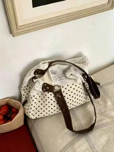 Detailed view of white polka dot canvas shoulder bag with brown straps and lace trim.