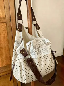 Detailed shot of the polka dot and white lace spliced hobo shoulder bag with brown straps.