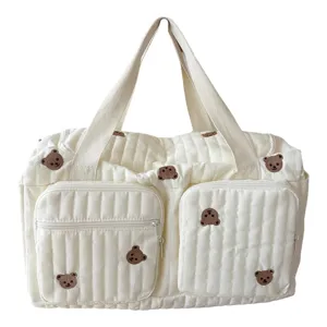 Detailed shot of quilted travel bag with cute brown bear embroidery and front pockets.