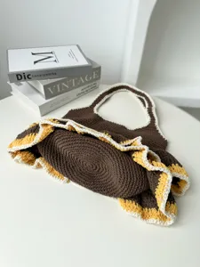 Handgemachte Häkelstrick-Tote-Bag-Detail, lässige braune Beuteltasche mit gelb-weißem Rüschenrand.