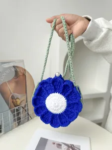 Handmade crochet blue flower shoulder bag with white center pearl closure and green strap.