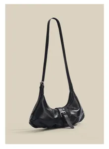 Detailed close-up view of minimalist black leather crossbody dumpling bag with pleats.