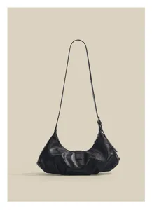 Detailed shot of the black minimalist crescent shoulder bag showing its unique pleated design.