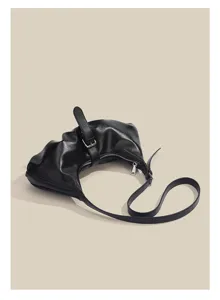 Black faux leather crescent shoulder bag, detailed zipper closure and chic strap buckle design.