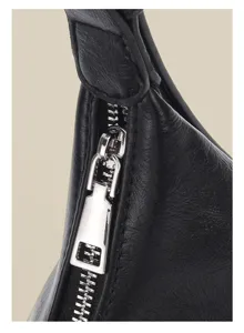 Detailed close-up view showing the sleek zipper and leather texture of a black shoulder bag.