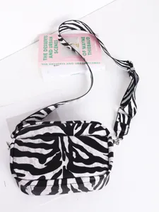 Detailed view of women's black and white zebra print crossbody bag with wide strap and hardware.