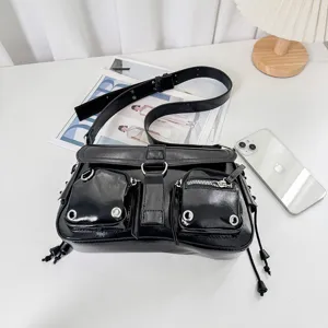 Black patent leather shoulder bag detail, featuring front pockets, metal rings and zippers.