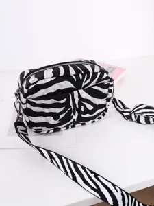 Close-up detail view of a stylish black and white zebra pattern crossbody bag with a wide strap.
