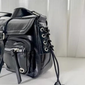 Detail shot of a chic black leather motorcycle shoulder bag with stylish grommets and zippers.