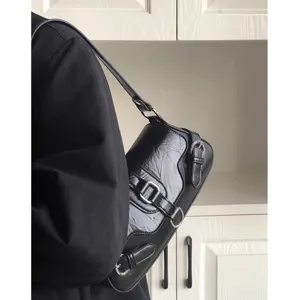 Detailed shot of a black crinkled leather motorcycle shoulder bag with stylish metal buckles.