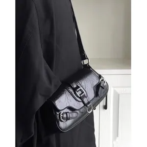 Detail view of the black motorcycle style underarm bag, showing leather texture and buckles.
