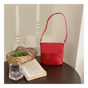 Red bucket shoulder bag detail shot, simple flap design, elegant daily lifestyle aesthetic.