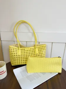 Detail view of the yellow hollow woven tote bag and matching pouch in a lifestyle setting.