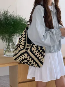 Crochet straw tote bag detail showing black and white pattern and wooden bead strap design.