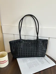 Close-up view of black woven tote bag with cutout grid design, chic and spacious for daily use.