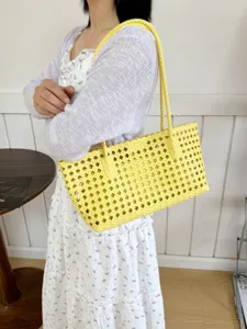 Detail view of yellow woven leather shoulder bag, hollow design, summer fashion tote.