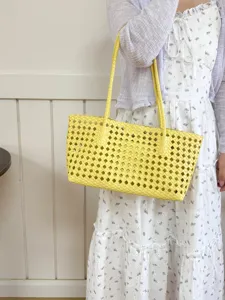 Detail shot of a stylish yellow hollow-out woven tote bag, perfect for summer daily commuting.