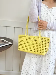 Detailed view of a stylish yellow woven tote bag worn by a model, perfect for summer daily commute.