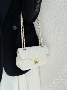 Close-up detail of a white quilted leather shoulder bag featuring an elegant gold chain strap.