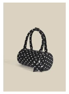 Detailed view of black and white polka dot cylindrical handbag with chic star charm.