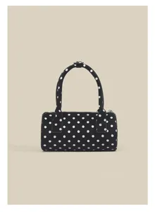 Detailed view of the chic black and white polka dot cylindrical handbag with top handle.
