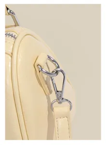 Close-up detail of light yellow Boston shoulder bag hardware and strap clasp, premium quality.