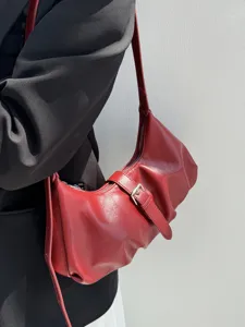 Red minimalist crescent shoulder bag detail view with metal buckle and soft leather.