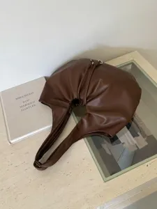 Brown slouchy shoulder bag detail, chic pleats design, elegant commuter handbag for daily use.