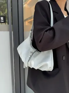 Minimalist light blue underarm shoulder bag detail shot, stylish everyday hobo accessory.