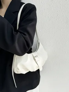 Close-up detail of the elegant white shoulder bag with buckle strap and smooth leather texture.