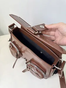 Brown patent leather shoulder bag interior detail showing multiple zipper pockets and closure.