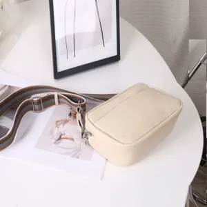 Detailed view of an off-white PU leather crossbody bag with a wide striped strap.