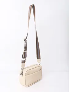 Detail view of a beige PU leather crossbody bag with a striped adjustable fabric strap.