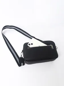 Detailed view of black PU leather crossbody bag with striped strap and front zipper pocket capacity.