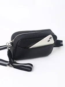 Closeup of black PU leather crossbody bag showing front pocket holding phone and textured fabric.