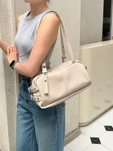 Detailed view of the stylish beige shoulder bag with chic side buckle straps for women.