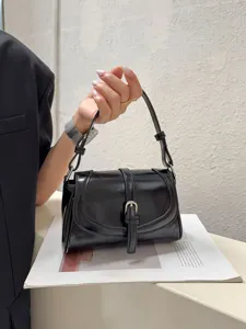 Glossy black leather shoulder bag detail, vintage flap design with metal buckle closure.