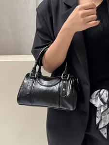 Black patent leather boston handbag detail, stylish studded hardware commuter shoulder bag.